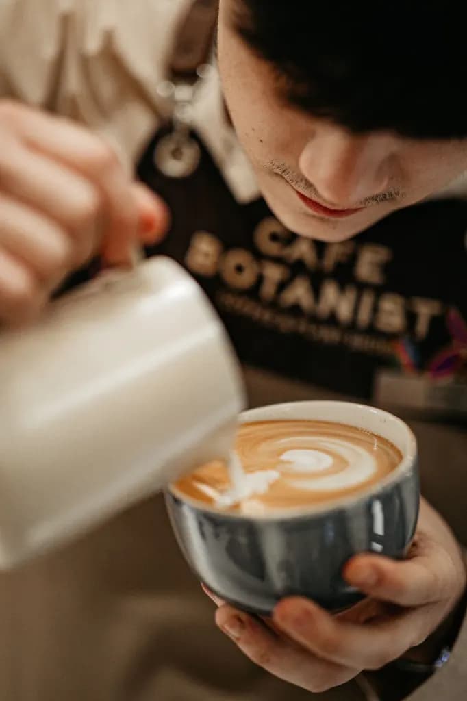 Barista gießt Milchschaum in eine Tasse